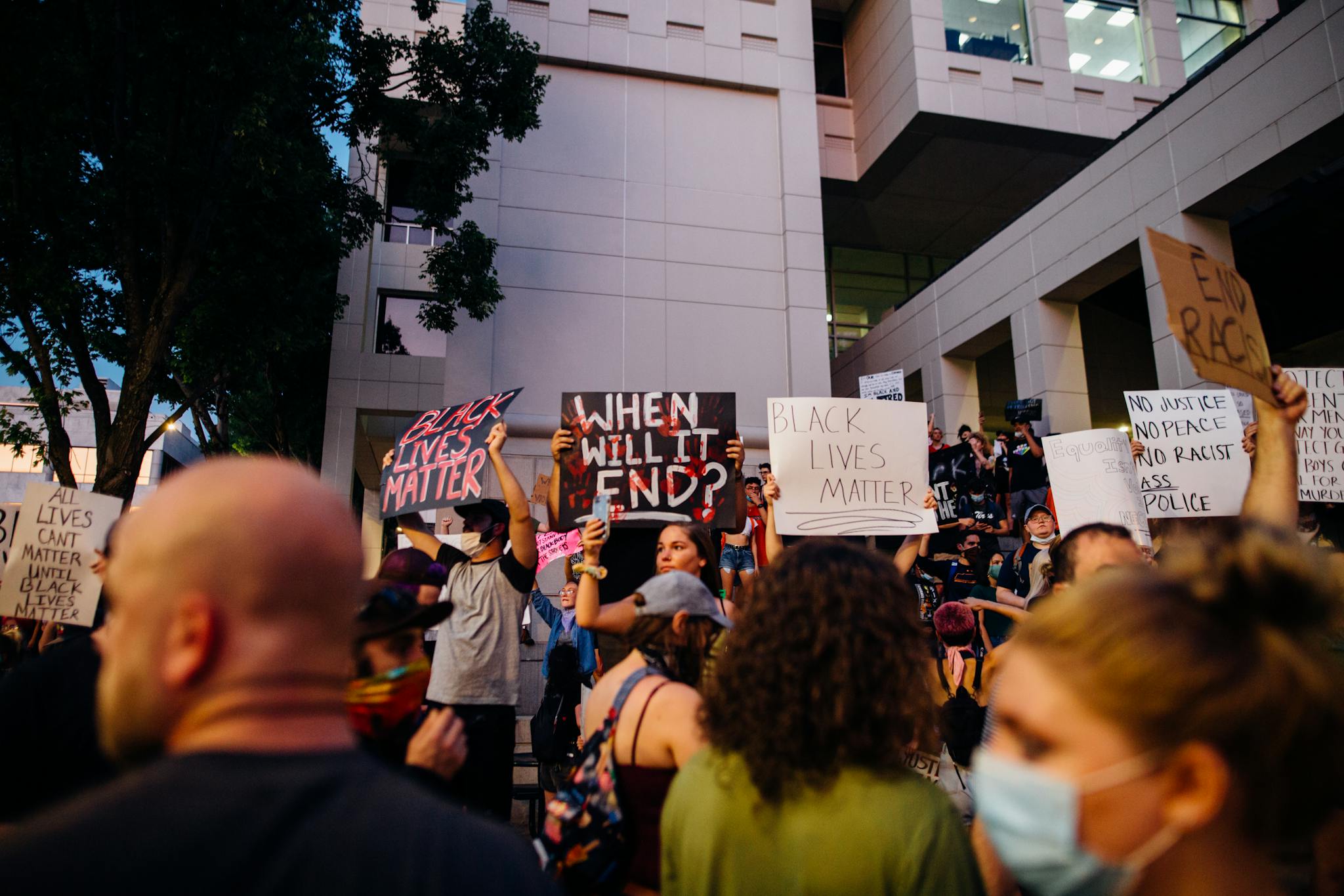 A crowd of activists at a Black Lives Matter protest holding signs advocating for racial justice.