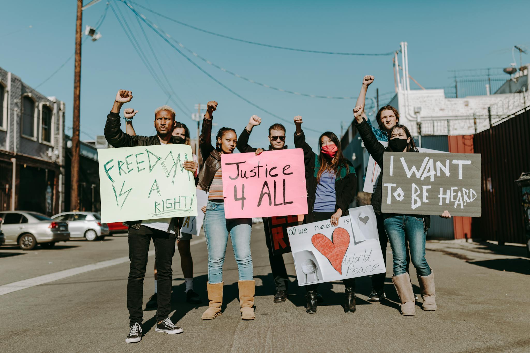 A diverse group of protesters holding signs advocating for justice, freedom, and world peace.