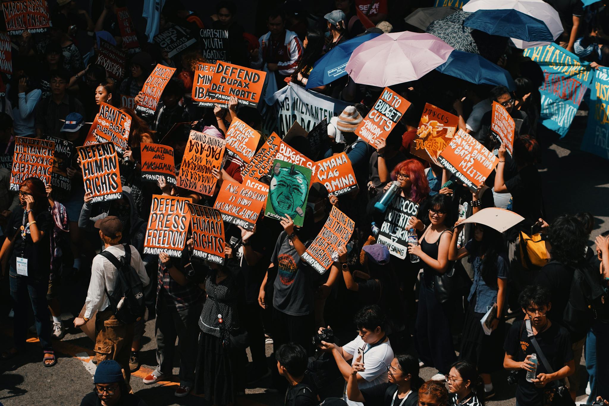 Crowd gathering with colorful signs demanding human rights and freedom in a peaceful protest.